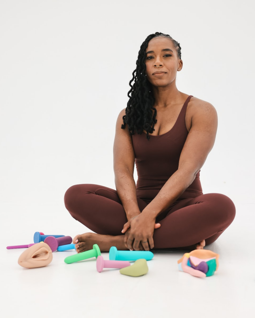 Dr. Hope L. Hayes, pelvic floor therapist, seated on the floor with pelvic anatomy tools