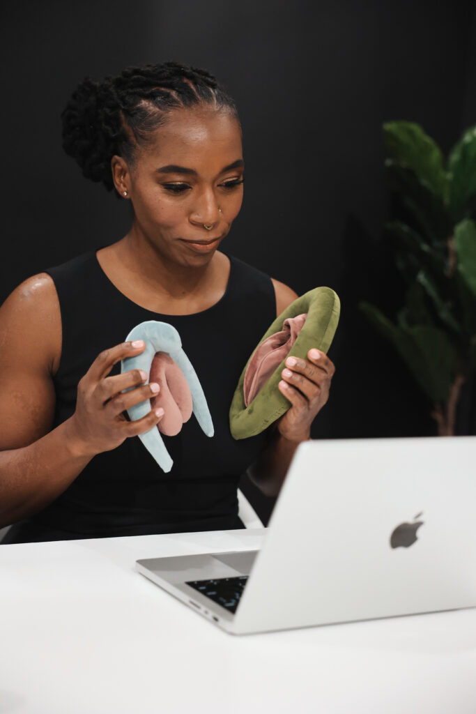 Dr. Hope L. Hayes conducting an online pelvic floor therapy session, holding anatomical pelvic models to explain vaginal health concepts
